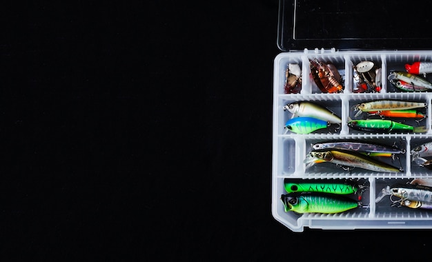 Various colorful fishing lure box on black background