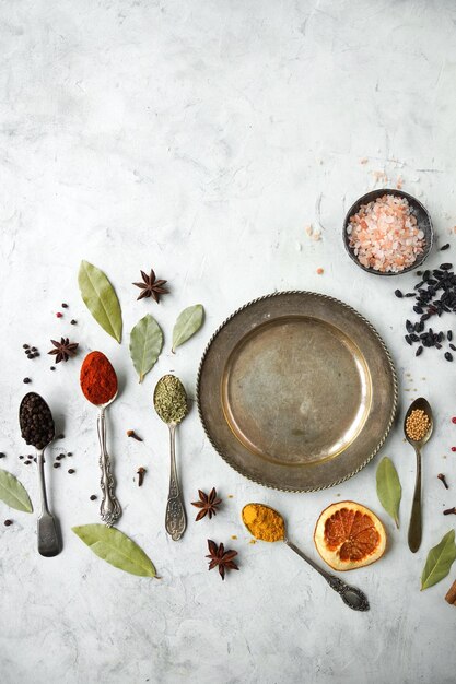 Various colorful indian spices and herbs in silver spoons on white background Healthy lifestyle organic food top view space for text