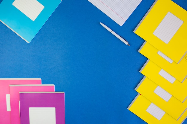 various colorful school notebooks on blue 