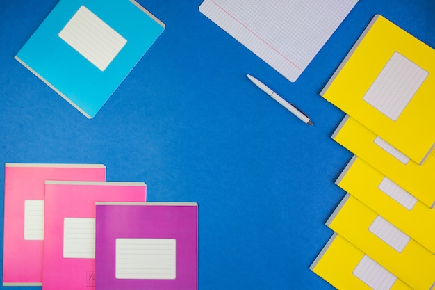 various colorful school notebooks on blue 
