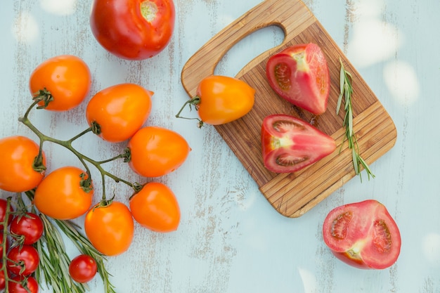 Various colorful tomatoes and rosemary herb on a light blue