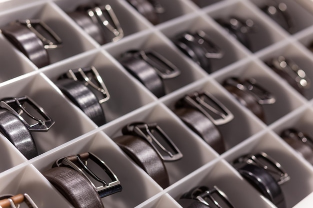 Various coloured leather belt display on shelf in the store in a men clothing boutique