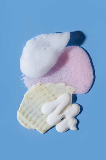 Various cosmetic mask, creams, serum, scrub and lotion smear on a blue background. Beauty texture. Sample of a cosmetic product.