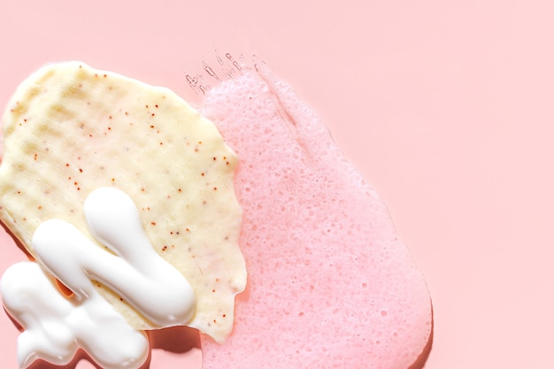 Varie maschere cosmetiche, creme, siero, scrub e lozioni su uno sfondo rosa. trama di bellezza. campione di un prodotto cosmetico.