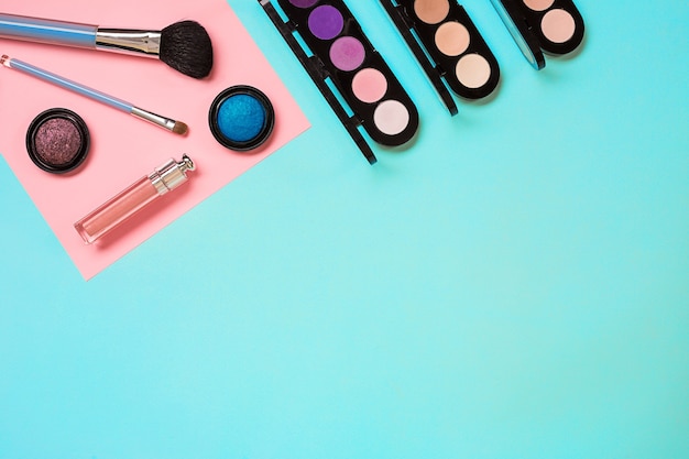 Various cosmetics and brushes on blue background