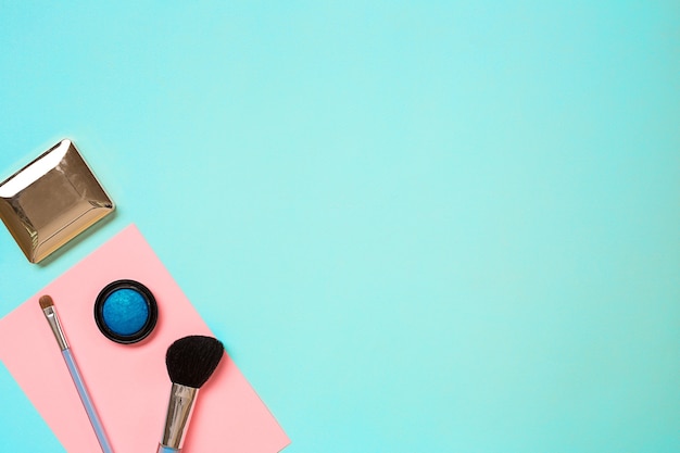 Various cosmetics and brushes on blue background