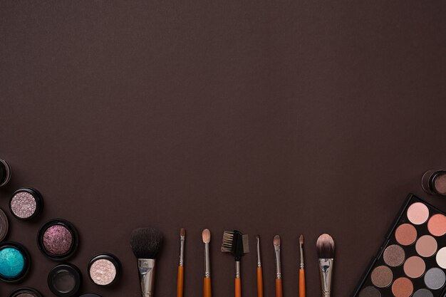 Various cosmetics and brushes on brown background. Top view. Still life. Copy space