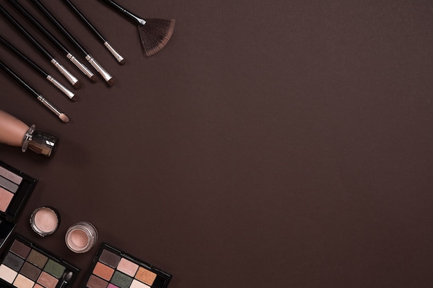 Various cosmetics and brushes on brown background