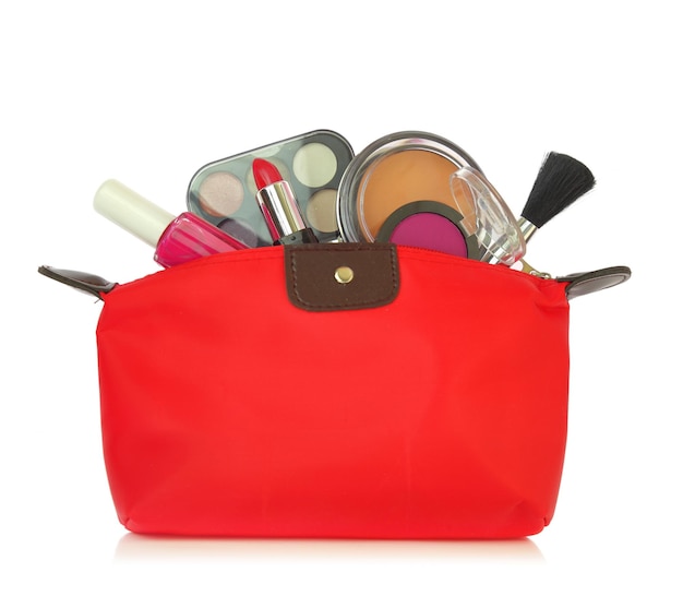 Various cosmetics coming out of a red bag isolated on white