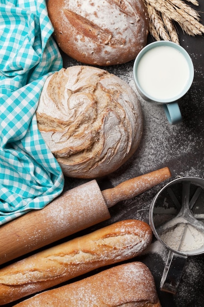 Various crusty bread and cup of milk on blackboard background. Top view