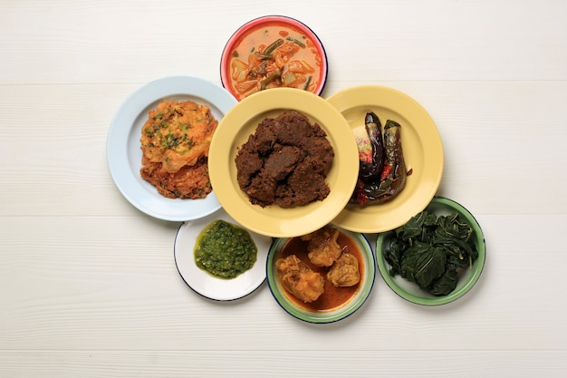 Various Culinary from Padang Called Masakan Padang or Padang Dishes. Popular Dishes in Indonesia Originally from Minang, West Sumatra, Serve on Layer of Stacked Plate on White Background