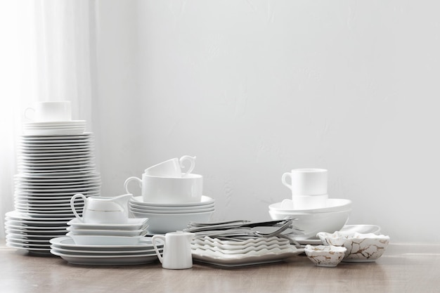 Various cutlery on a wooden table against a white wall