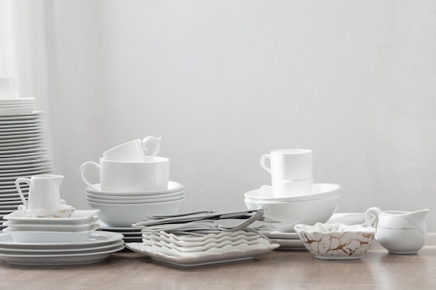 Various cutlery on a wooden table against a white wall