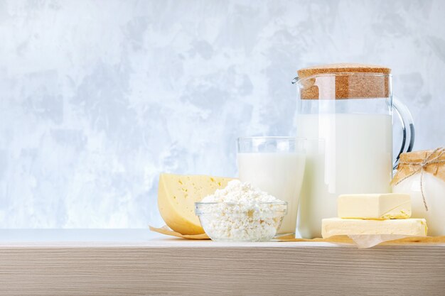 Various dairy products on wooden table against grey background with copy space.