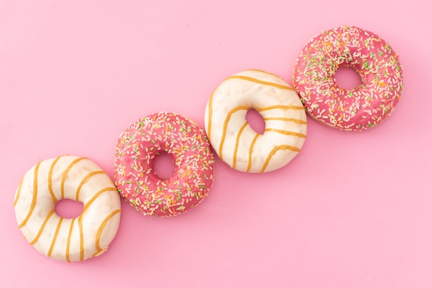 Various decorated doughnuts in motion falling on pink background. Sweet and colourful doughnuts falling or flying in motion. 