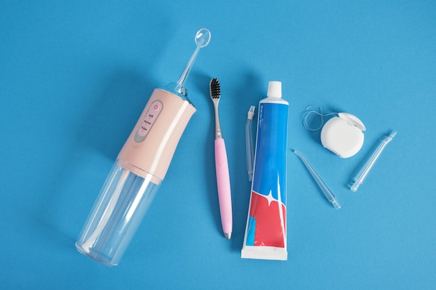 Various dentifrices on a blue background a set of teeth cleaning dental floss brush irrigator toothpaste