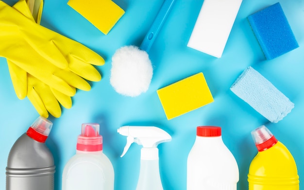 Various detergents and cleaning products agent, sponges, napkins and rubber gloves, blue background. Top view