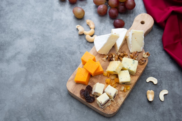 Various different types of cheese slices, cheese mix on wooden cutting board. 