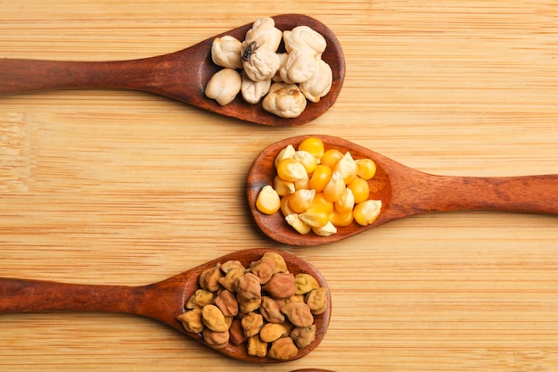 Various dried types of bean and pea in wooden spoon.