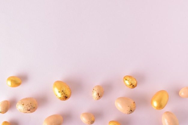 Various Easter eggs of yellow shades lie on a pink background Easter background with painted eggs and sequins Copy space Flat lay top view