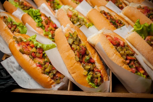 Various fast food snacks Hotdog with fresh salad cucumbers tomatoes and onions Soft focus