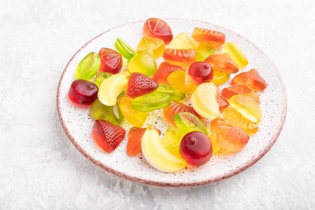 회색 콘크리트 배경에 접시에 다양한 과일 젤리 사탕