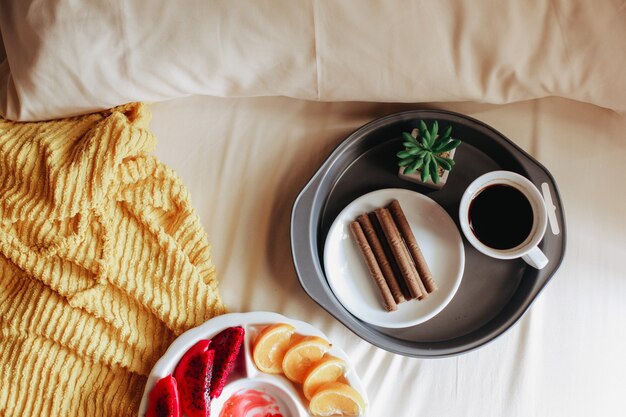 Various fruit with snack and a cup of coffee for breakfast on the bed