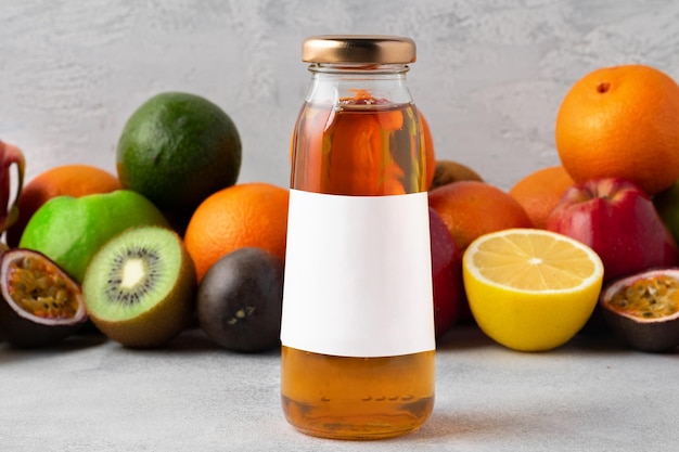 Various fruits and freshly squeezed fruits juice in bottle on gray background