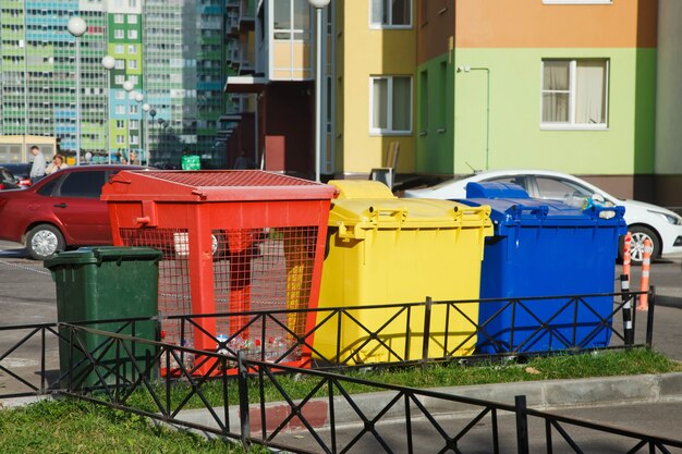 Photo various garbage bins for separate collection of garbage. colorful plastic containers for sorting household waste on street. recycling of household waste. environmentally friendly garbage collection