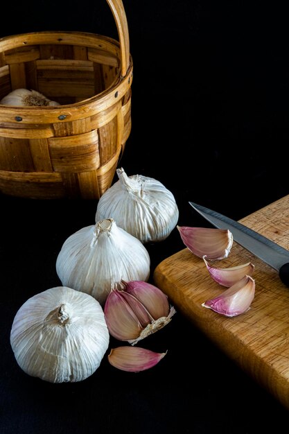 Foto vari garlics e anche spicchi d'aglio su un tagliere di legno accanto a un coltello da cucina isolato ag