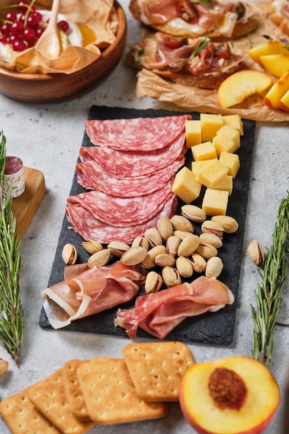 Various gourmet wine snacks. Blueberries, peaches, salami, prosciutto, pistachio, pine nuts, various cheeses, camembert cheese and herbs. Italian snacks for an important holiday.