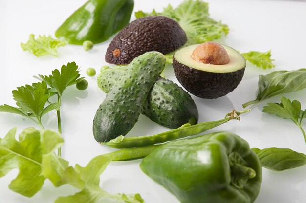 Various green vegetables on a light background, top view