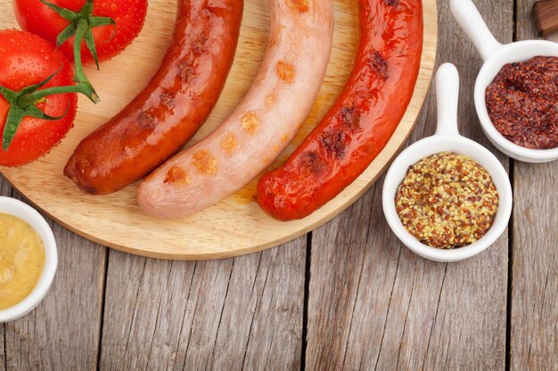 Various grilled sausages with condiments and tomatoes