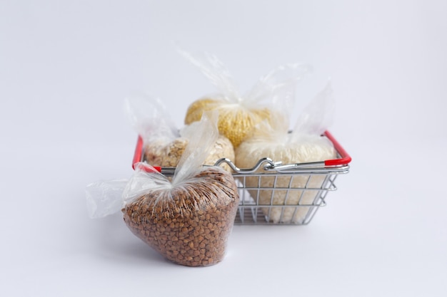 Various groats in packages in grocery basket. Rice and oatmeal buckwheat and millet