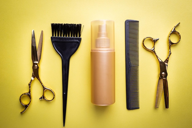 Various hair dresser and cut tools on yellow background with copy space