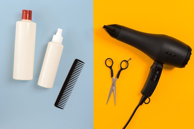 Various hair styling devices on the color blue, yellow paper background, top view. Copy space. Still life. Mock-up. Flat lay