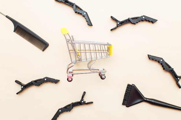 Various hairdressing tools with shopping cart on a beige background beauty salon concept