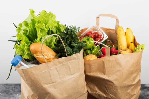 Various healthy food in paper bag on gray space