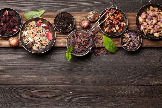 Various herbal dry tea in bowls on wooden table Top view with copy space Flat lay