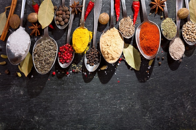 Various herbs and spices for cooking on dark, top view