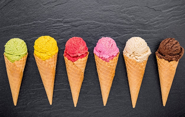 Various of ice cream flavor in cones set up on dark stone