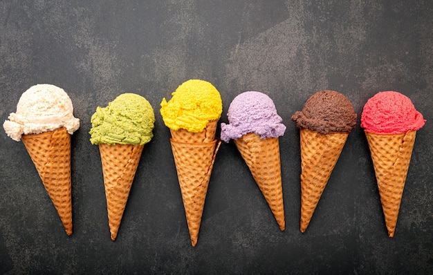 Various of ice cream flavor in cones setup on dark stone background .