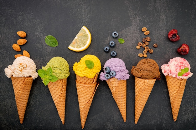 Various of ice cream flavor in cones setup on dark stone background .