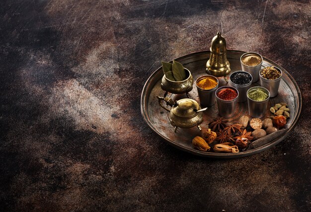 Various Indian spices, spicy and
  seasoning in a metal tray on a dark background, copy space for text