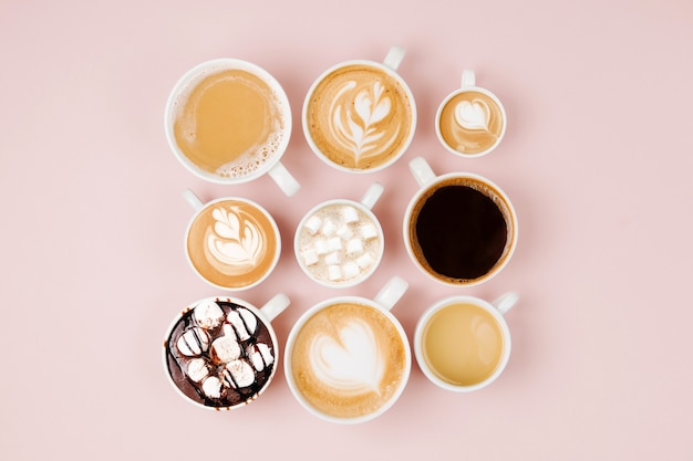 various kinds of coffee in cups of different size   on pale pink background.  coffee  time concept.  flat lay, top view