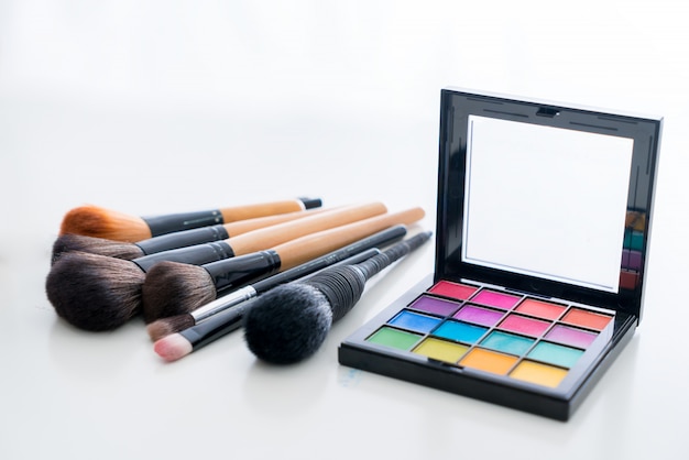 Various make up brush with make up products and concealers cosmetics on table in white background.