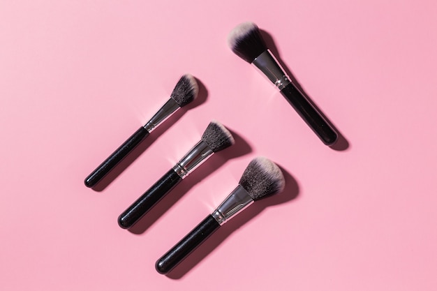 Various makeup brushes on pink background top view cosmetics and beauty concept