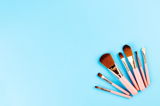 Various Makeup Brushes pink set with empty frame for text on blue paper