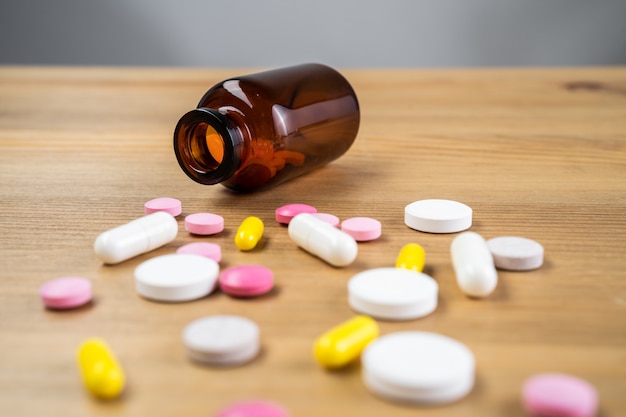 Various medications and vitamins, a pill bottle. Wooden background, place to insert your text. Health and pharmacy.