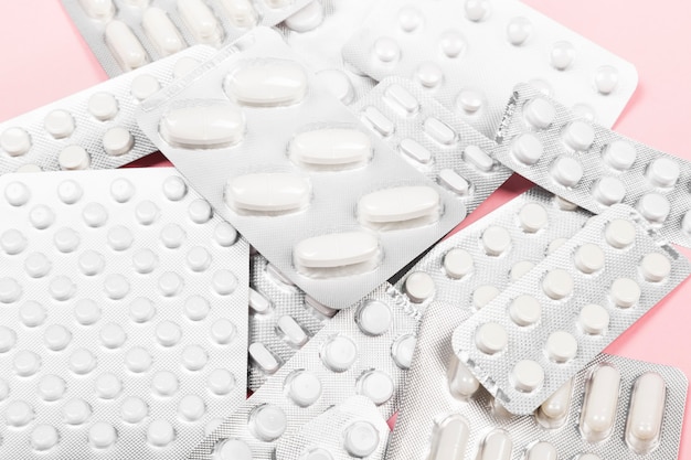 Various medicine pills on pink surface